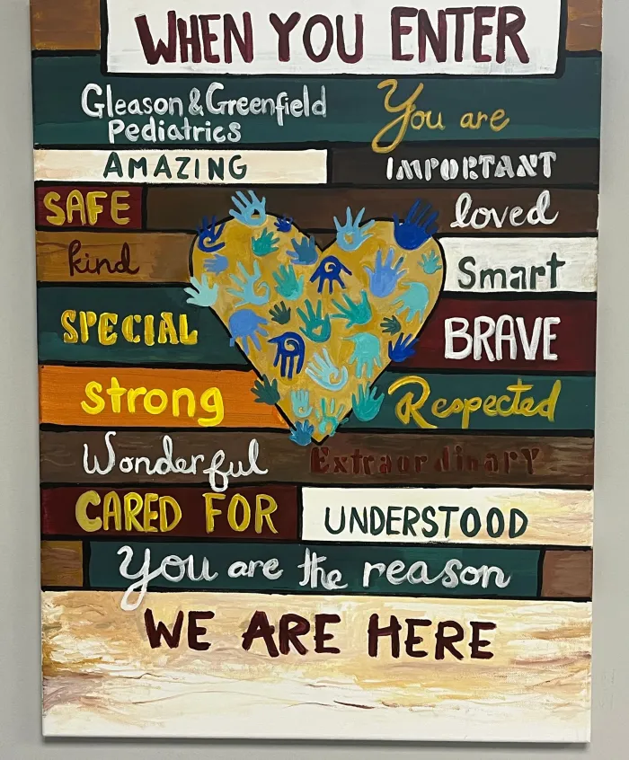 Painted board reading &ldquo;When you enter, you are amazing, safe, loved, you are the reason we are here&rdquo;