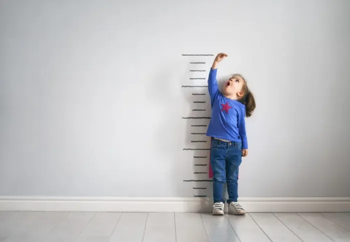 A child standing against a growth chart
